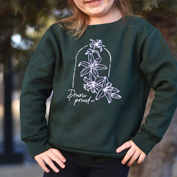 A child wearing a green crewneck sweater with a floral design and the text 'Prairie Proud' on it.