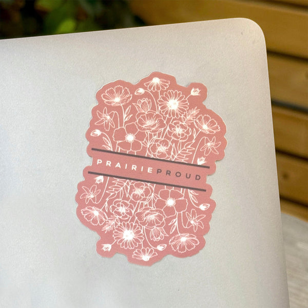 A die cut vinyl sticker with a floral design and the text 'PRAIRIE PROUD' on a laptop.