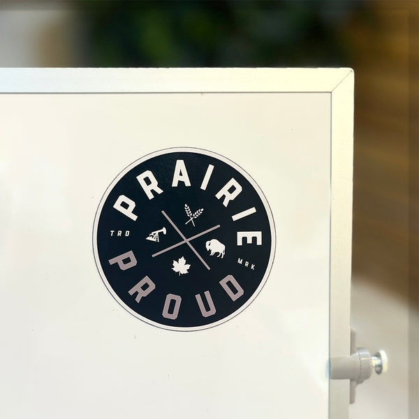 A circular black and grey magnet with the text 'PRAIRIE PROUD'.