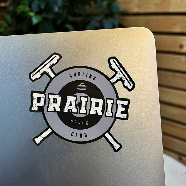 A vinyl sticker with text and graphics related to curling placed on a laptop.