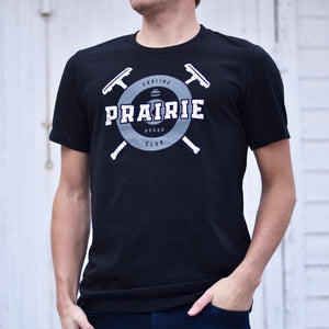 A person wearing a black crew t-shirt with the text 'prairie proud' and a curling inspired design.