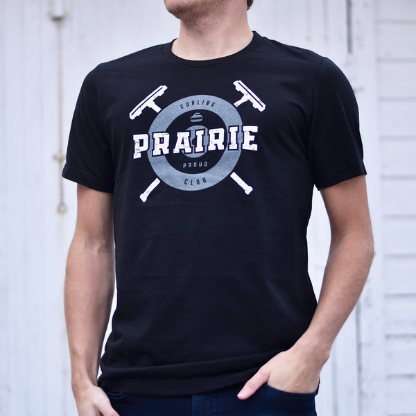A person wearing a black crew t-shirt with the text 'prairie proud' and a curling inspired design.