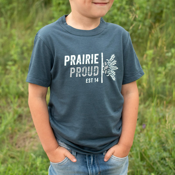 A child wearing a grey crew t-shirt with the text 'PRAIRIE PROUD EST 14' and a wheat graphic on it.