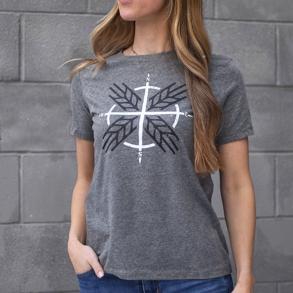 A female model wearing a heather grey t-shirt with a compass design on the front.