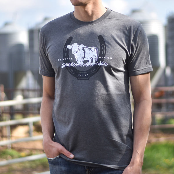Person wearing a grey t-shirt with a cow graphic and the text 'prairie proud'.