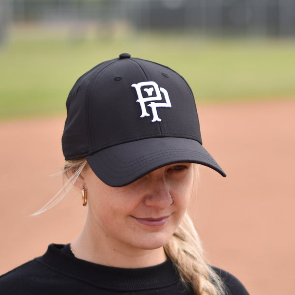 A person wearing a black baseball cap with white embroidery of a monogram on the front.
