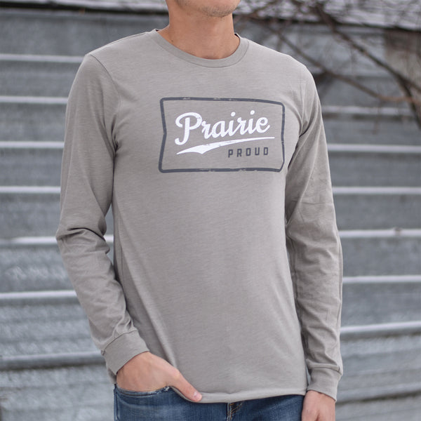 A person wearing a long-sleeved gray crew t-shirt with 'Prairie Proud' text on the front.