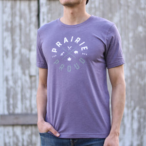 A person wearing a heather lavender coloured t-shirt with the text 'PRAIRIE PROUD' on it.