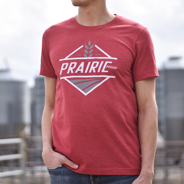 A person wearing a red t-shirt with the text 'Prairie proud' printed on the front with square wheat design.