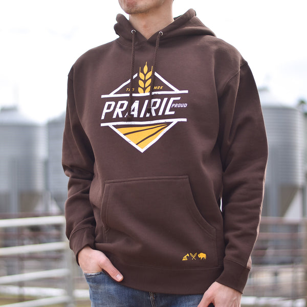 A person wearing a brown hoodie with the text 'Prairie proud' printed on the front with a yellow square wheat design.