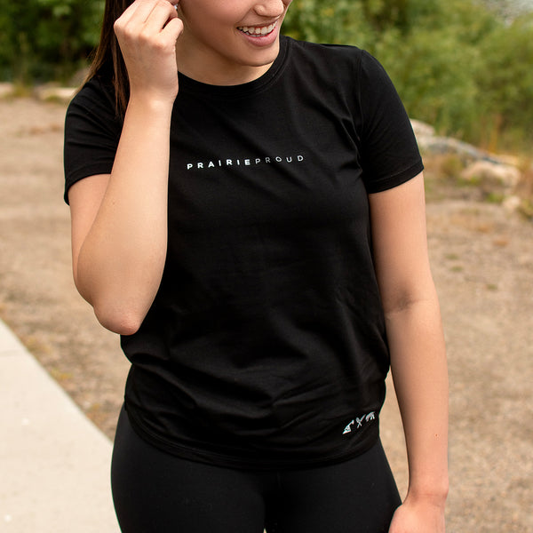 A female model wearing a black athletic crew t-shirt with the text 'PRAIRIE PROUD' across the chest.