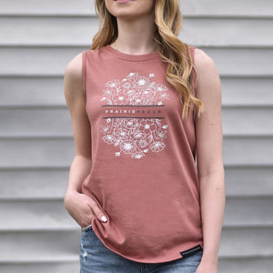 A woman wearing a sleeveless dusty rose tank top with a floral design and the text 'prairie proud'.