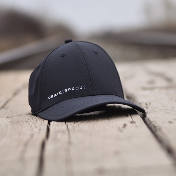 A black flexfit hat with 'PRAIRIE PROUD' text on the front, lower right side.
