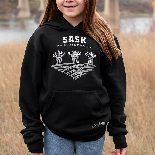 A child wearing a black hoodie with 'SASK Prairie Proud' text and a graphic design on the front.