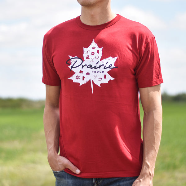 Person wearing a red t-shirt with a white maple leaf design and 'Prairie Proud' text outdoors.