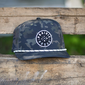Camouflage cap with a circular logo that says 'Prairie Proud' on the front.