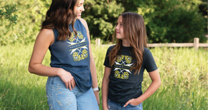 Woman and Child in a field wearing a tank top and t-shirt respectively featuring canola flowers