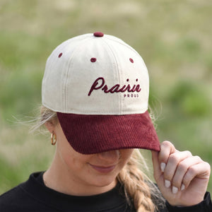 Female wearing a low crown corduroy cap with 'Prairie Proud' text in a natural setting