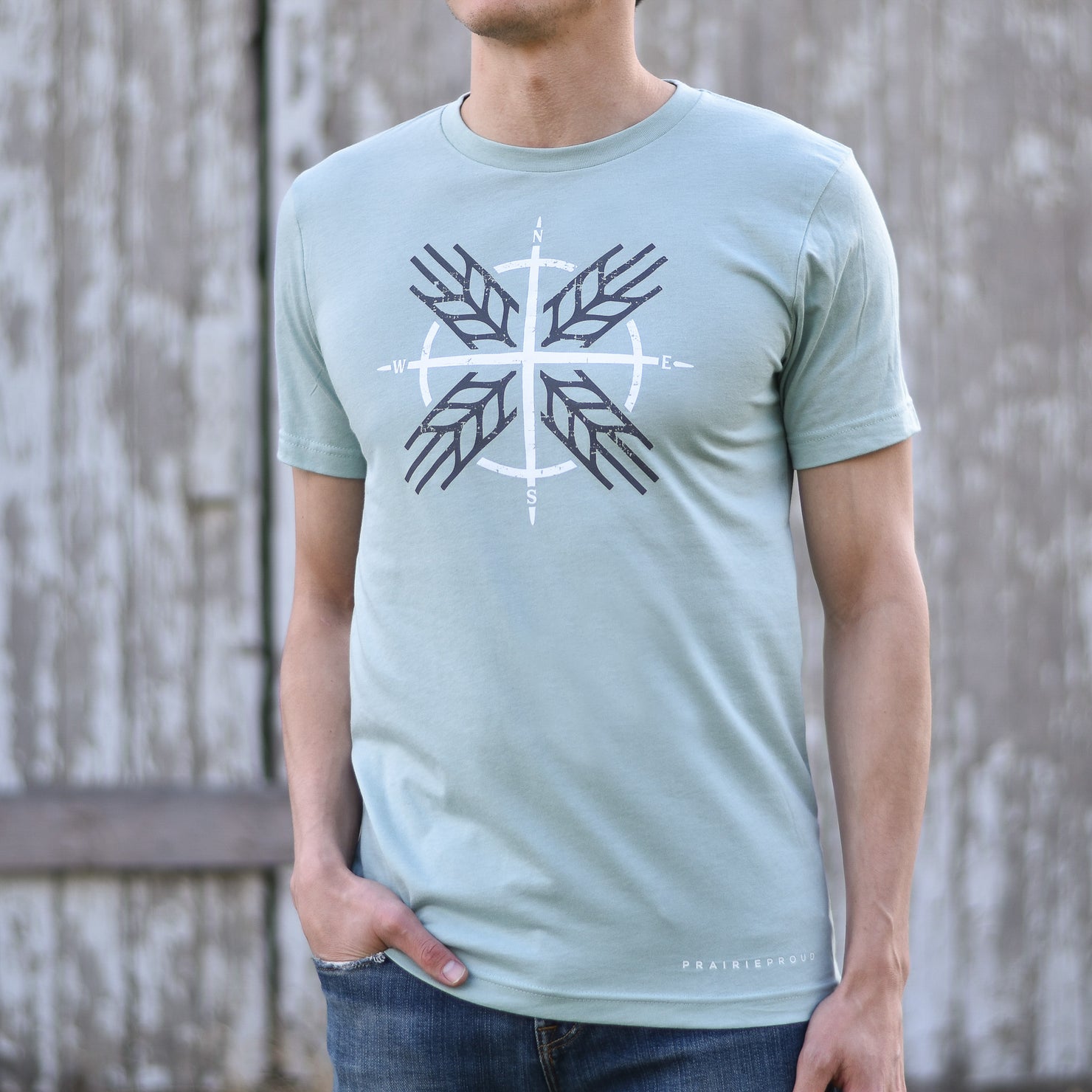 A person wearing a light blue t-shirt with a compass design on the front.