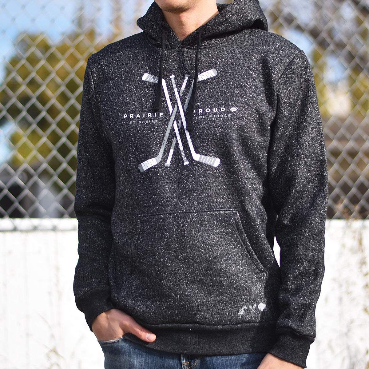 A person wearing a heather charcoal hoodie with a graphic of hockey sticks in the center.