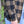 Close-up of a person wearing a brown and black buffalo plaid flannel shirt with a white embroidered 'PP' monogram logo on the cuff, paired with light blue jeans.