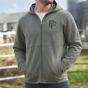 Person wearing a green hoodie with a monogram PP logo in an outdoor setting
